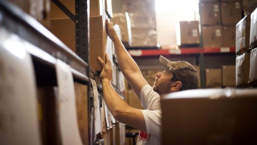 worker-reaching-up-for-cardboard-box-stored-in-war-2022-03-07-23-57-07-utc-scaled